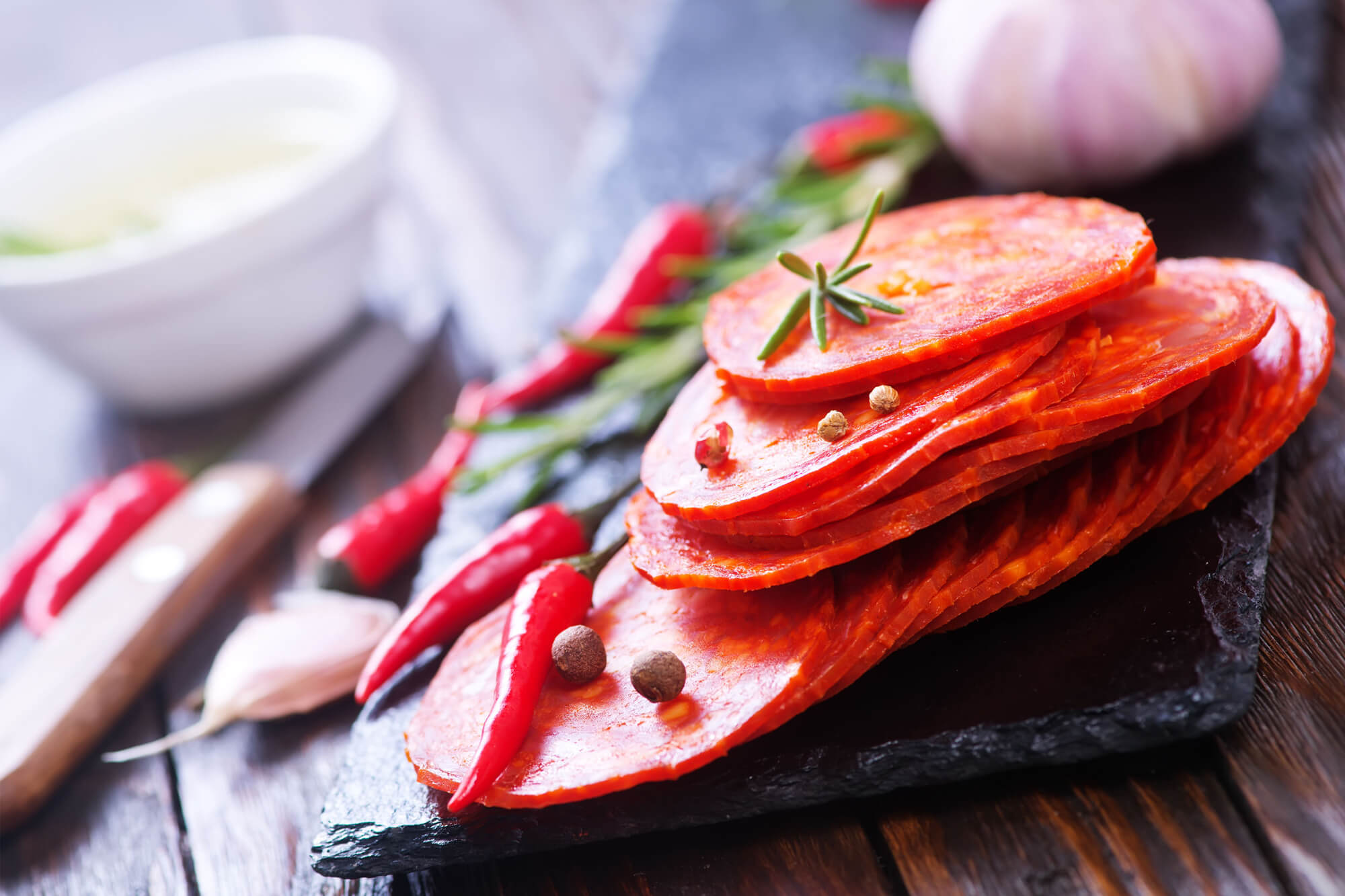 Griffith Tours contact page image of sliced salami and chilli on a black board.